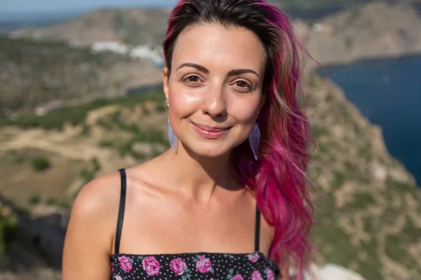 Bright girl stands in a mountainous area against the background of a sea view