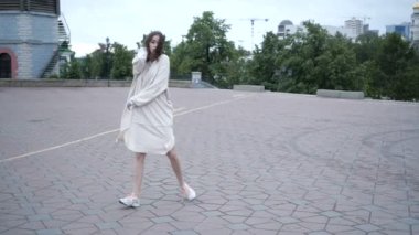 Genç bir kız öğrenci sıcak rüzgarlı havada şehirde dolaşıyor.