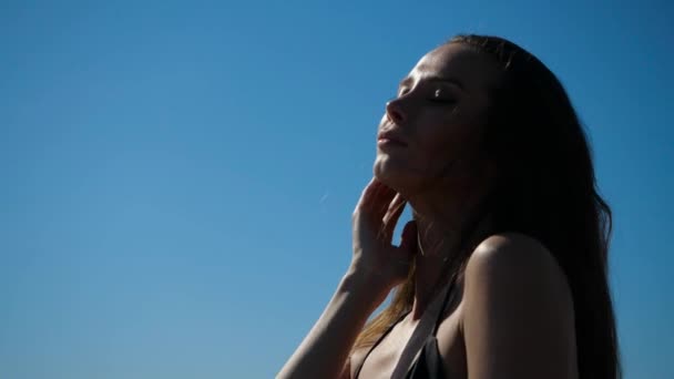 Açık yaz kıyafetleri içinde, gökyüzüne karşı duran çekici bir kızın portresi. — Stok video