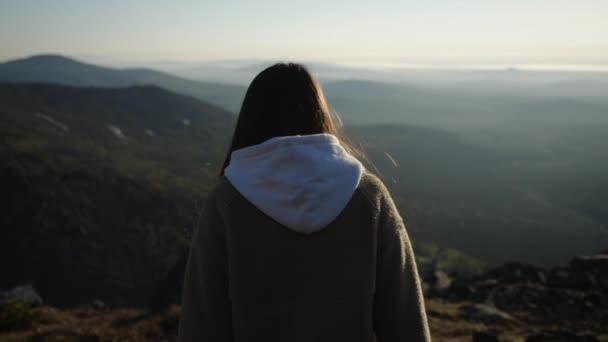 Video di una ragazza bruna con una giacca incappucciata che cammina in una zona montuosa — Video Stock