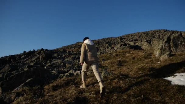 Un viaggiatore solitario ragazza cammina in salita a piedi attraverso il terreno montagnoso — Video Stock