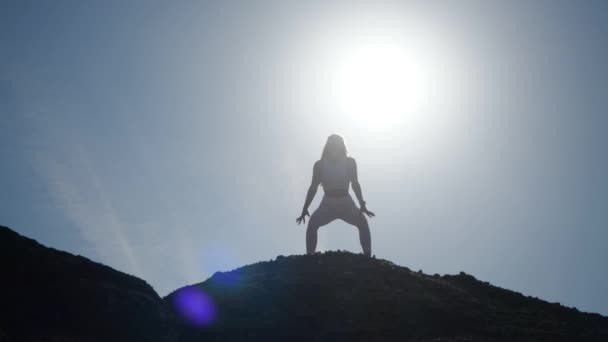 The figure of a girl athlete performing a squat exercise on the mountain — Stok video