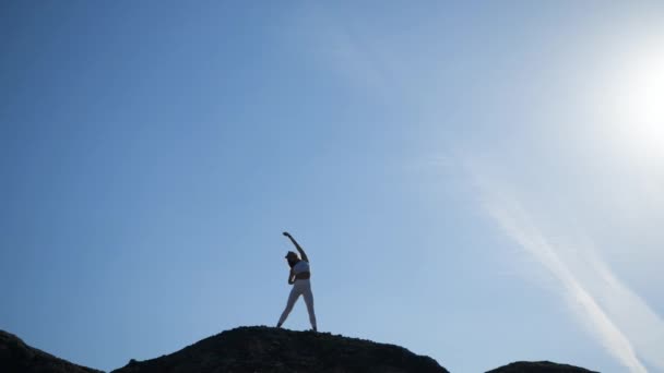 A female athlete standing on top of a mountain performs an exercise — 비디오