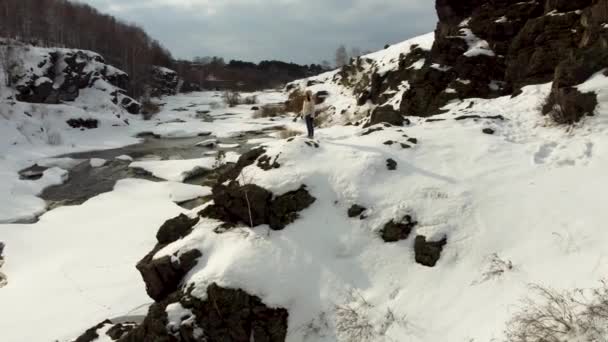Video from the height of a lonely girl stands on top of a snow-covered mountain — Stockvideo