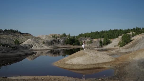 Shooting from afar a girl athlete in white sports uniform performs exercises — Video Stock