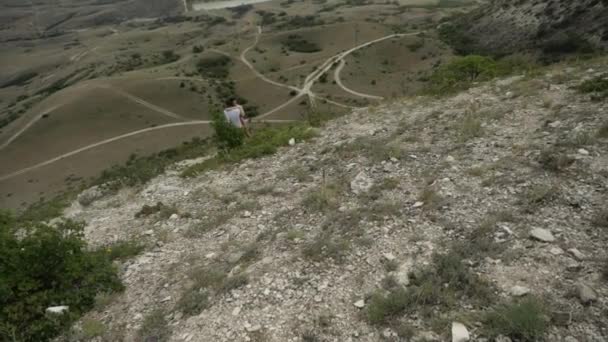 Dos jóvenes en una caminata por las montañas, parados y abrazados en clima cálido — Vídeo de stock