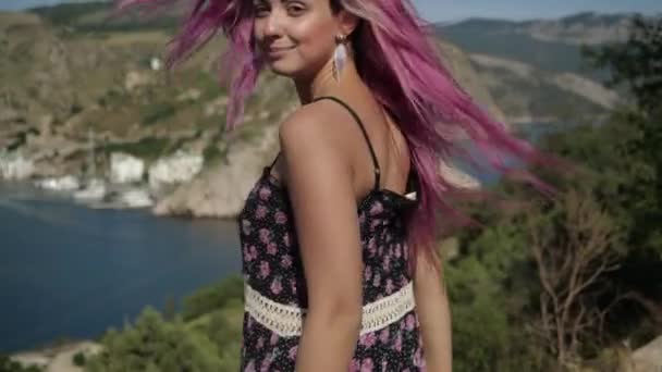 Відео портрет яскравої дівчини з фіолетовим волоссям, яка стоїть в горах — стокове відео
