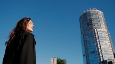 Siyah ceketli yalnız bir kız büyük şehirde sokakta duruyor.