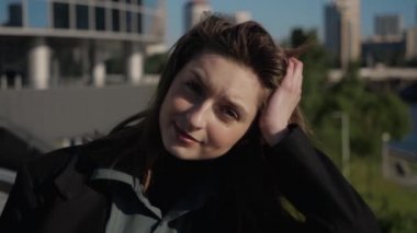Siyah ceketli tatlı esmer kız büyük şehrin setinde duruyor.