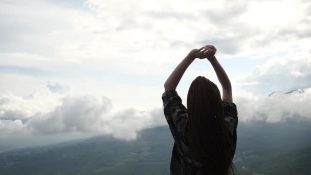 Una turista solitaria se para en la cima de una montaña y levanta las manos — Vídeo de stock