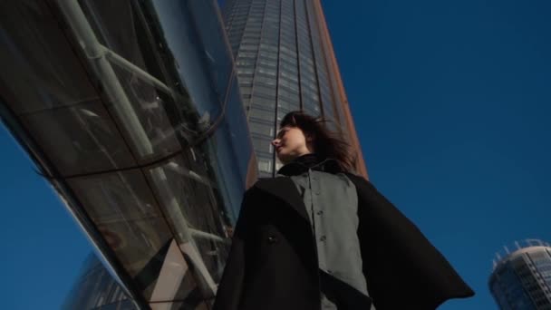 Dziewczyna stoi wśród metropolii na tle wysokiego budynku — Wideo stockowe