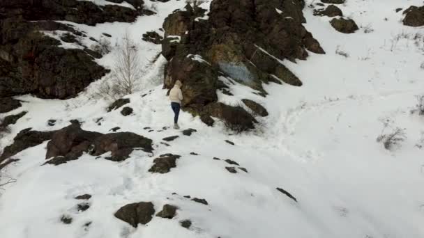 Een toeristisch meisje in wandelschoenen en een warme jas wandelingen in de besneeuwde bergen — Stockvideo