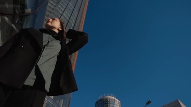 Eine Frau in einem Geschäftsviertel der Stadt steht in schwarzer Jacke und Bluse — Stockvideo