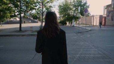 Takım elbiseli bir kadın elinde evrak çantasıyla şehirde dolaşıyor.