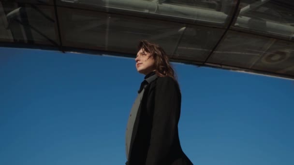 Front view of a lonely woman in business attire standing under a bridge — Stock Video