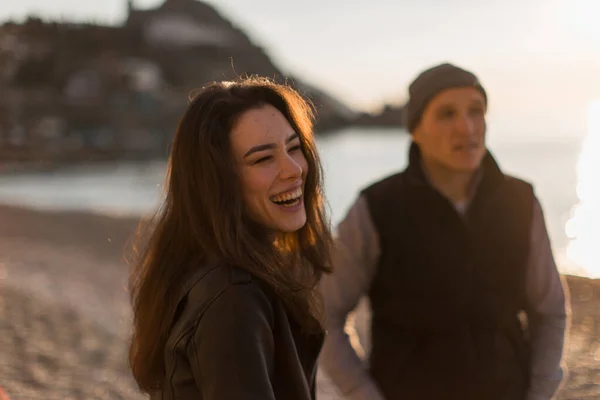 Attractive brunette girl and her boyfriend stand on the beach and laugh