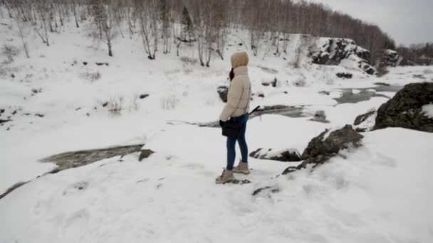 Una viajera se para en la montaña sosteniendo un palo selfie en su mano — Vídeos de Stock