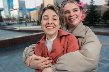 Güzel genç lezbiyen çift, birbirlerine nazikçe sarılıyorlar, gülümsüyorlar. 