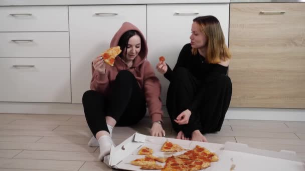 Estudiantes mujeres se divierten comiendo pizza y hablando sentado en casa en la cocina — Vídeos de Stock