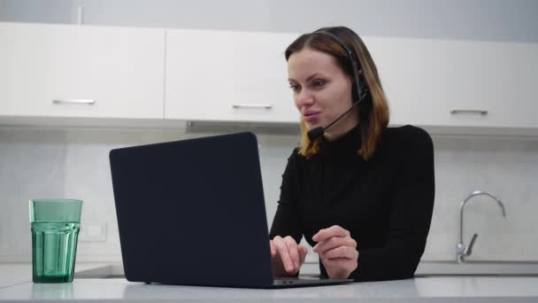 Een jonge vrouwelijke call center medewerker praat met een klant thuis zitten — Stockvideo