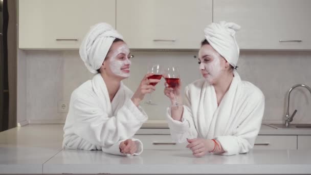 Δύο φίλοι με ρόμπες και πετσέτες στο κεφάλι διασκεδάζουν πίνοντας κρασί. — Αρχείο Βίντεο