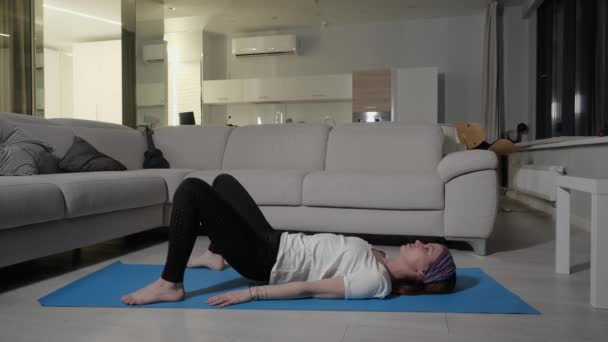 Ragazza sportiva esegue esercizio di footwork mentre sdraiato sul tappeto blu yoga a casa — Video Stock