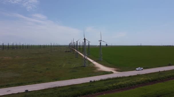 Parques eólicos brancos altos aguardam entre os belos campos verdes brilhantes — Vídeo de Stock