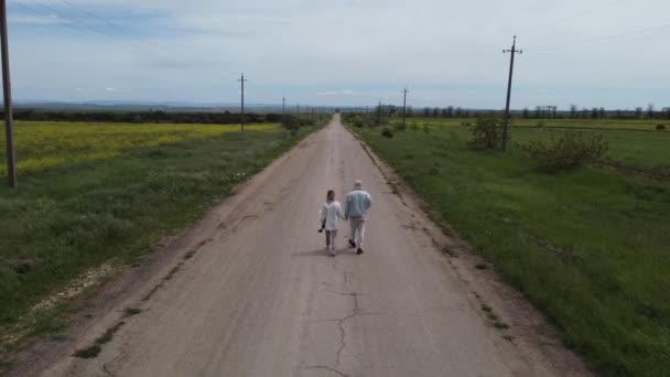 Kilku podróżników spaceruje pustą drogą trzymając się za ręce. — Wideo stockowe