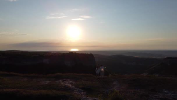 Dwóch podróżników stoi na szczycie góry i ogląda piękny zachód słońca. — Wideo stockowe