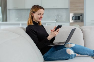 Güzel bir kız dizüstü bilgisayarın arkasında çalışırken telefonuna bir mesaj yazar. 