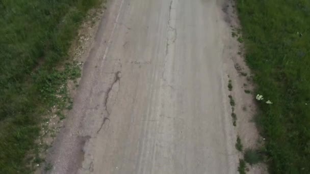 Um jovem casal cara e menina caminhar ao longo de uma estrada vazia entre os campos verdes — Vídeo de Stock