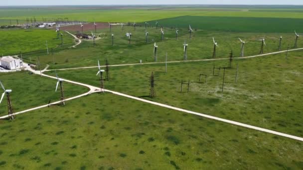 Farmy wiatrowe w pobliżu małego miasteczka, wśród zielonych pól. Strzelanie do drona — Wideo stockowe