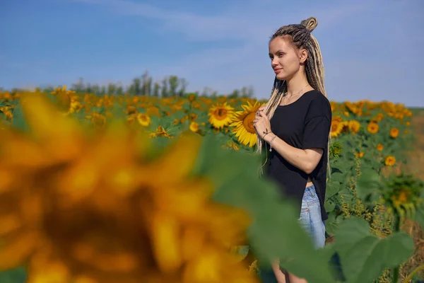 Retrato de uma menina que fica em um campo com girassóis floridos — Fotografia de Stock
