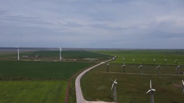 Berrak gökyüzünün ortasında yeşil tarlalarda bir sürü rüzgâr tarlası var.. 