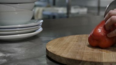 Erkek eli, kırmızı dolma biberi tahta kesme tahtasıyla keser.