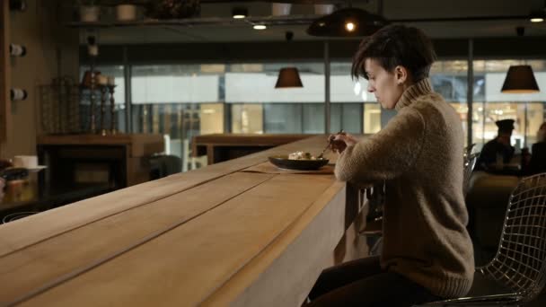 Ένα κορίτσι τρώει χαρούμενα κάθεται σε ένα εστιατόριο και μιλάει με το σερβιτόρο — Αρχείο Βίντεο