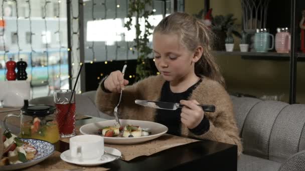 Gadis kecil yang lucu makan cheesecake dengan buah dan tersenyum — Stok Video