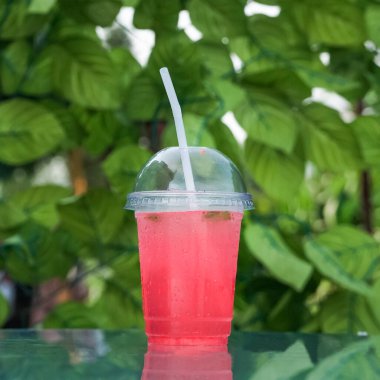 Kırmızı limonata, cam bir masanın üzerinde plastik tek kullanımlık camla.