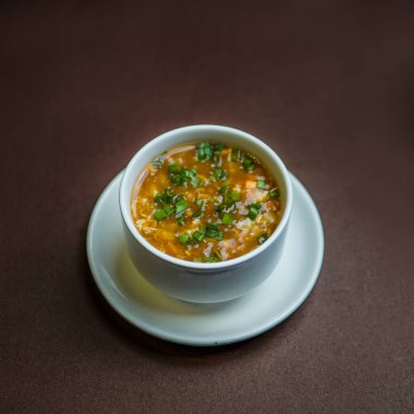 Chicken corn soup with vegetables and herbs in a bowl on a wooden tabe