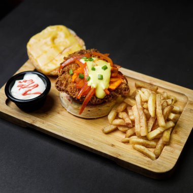 Beef Burger olive on top with fries and cheese in a wooden tray with mayo sauce and top removed