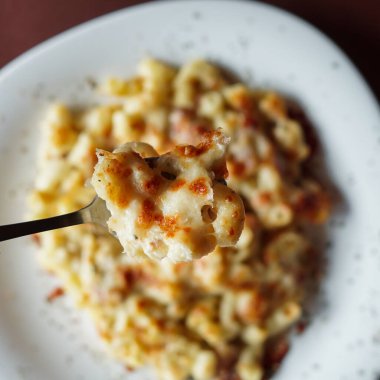 Tahta masadaki tabakta peynirli tavuk peynirli makarna.