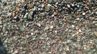 Deniz dalgaları kumsaldaki taş çakıl taşlarını birbirine yaklaştırıyor..
