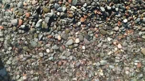 Морские волны крупным планом мелкой каменной гальки на пляже. — стоковое видео