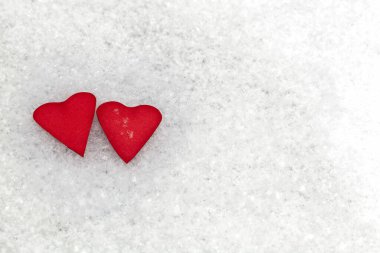 Beyaz karlı arkaplanda iki kırmızı kalp. İki kalp ve sevgililer günü..