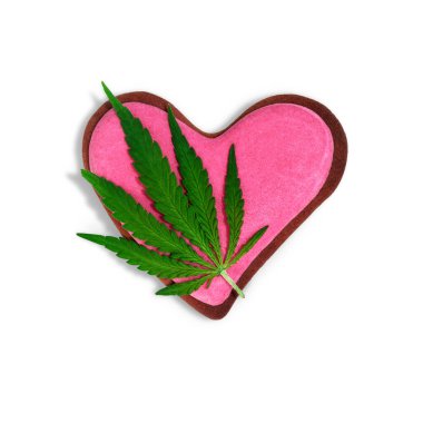 Esrar yaprağı ve dekore edilmiş kurabiyeler ile kompozisyon ve metin için kalp şeklinde alan, üst görünüm. Sevgililer Günü. Marihuana günü. Zencefilli ekmek ve kenevir yaprağı. Beyaz arka planda izole edilmiş zencefilli kek kalbi..