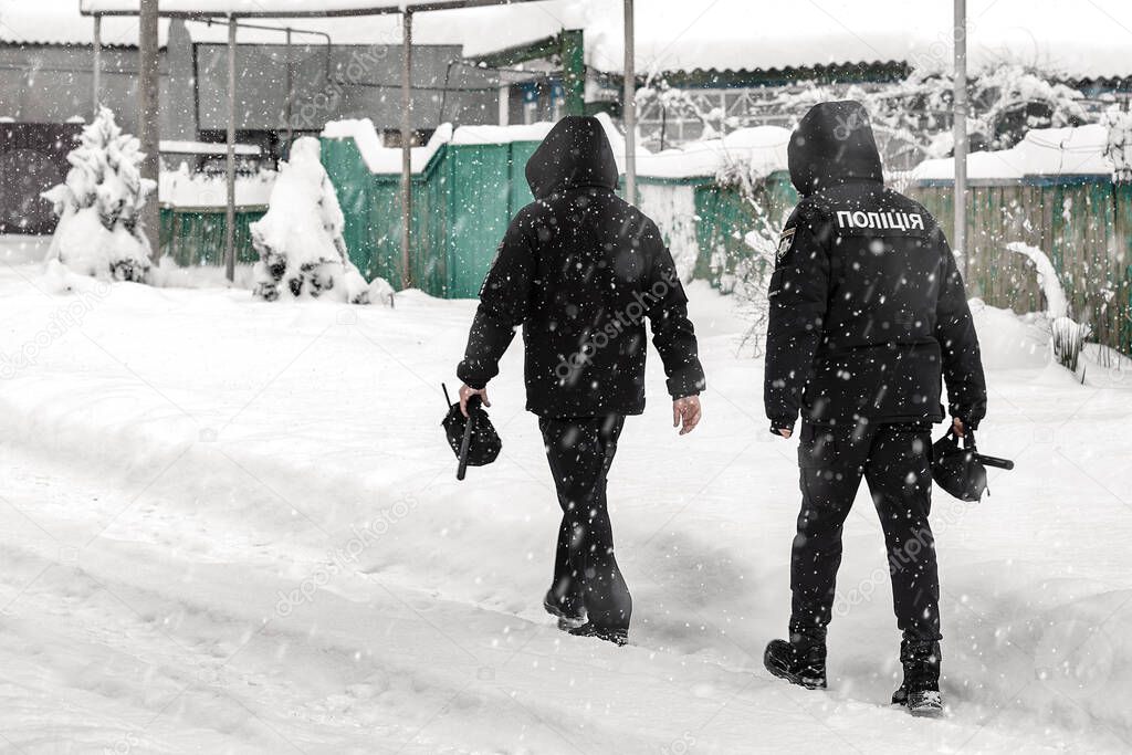 Two Ukrainian policemen walk a village street in snowy weather. Ukrainian police.