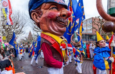 16 Şubat 2026. Mainz Rosenmontag Geçidi, Mainz, Almanya. MCV logosu olan Schwellkopp heykelciği ve neşeli katılımcı kalabalığı..