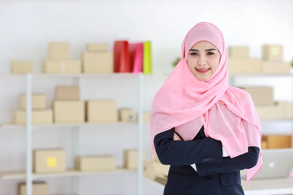 身穿蓝色西服 头戴粉色竖杆的亚洲宗教穆斯林妇女自信地站在那里 看着相机 商务妇女站在包装中小企业箱交付背景 家庭工作概念 — 图库照片
