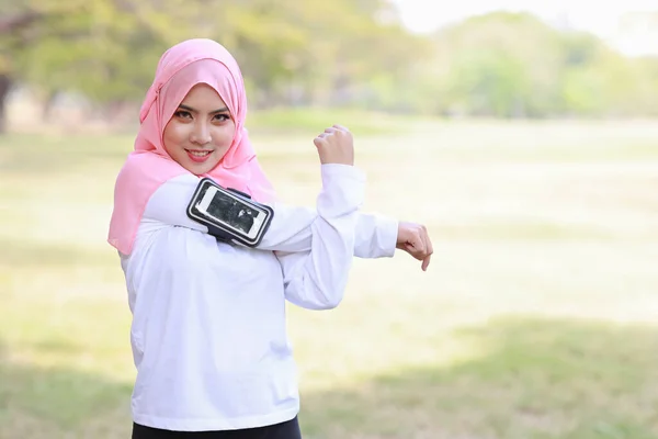 公衆運動のライフスタイルの概念は フィットネス女性は ワイヤレスイヤフォンや携帯電話から音楽を聞いて サイドビューアスレチック若いですアジアのイスラム教徒の女の子でスポーツウェアスタンディング ワークアウト後ストレッチ — ストック写真