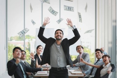 Çok ırklı iş adamları şirket projesinin coşkulu duygularıyla el ele tutuşuyorlar ve sonuç olarak toplantı odası ve düşen banknotlarla sonuçlanıyor.